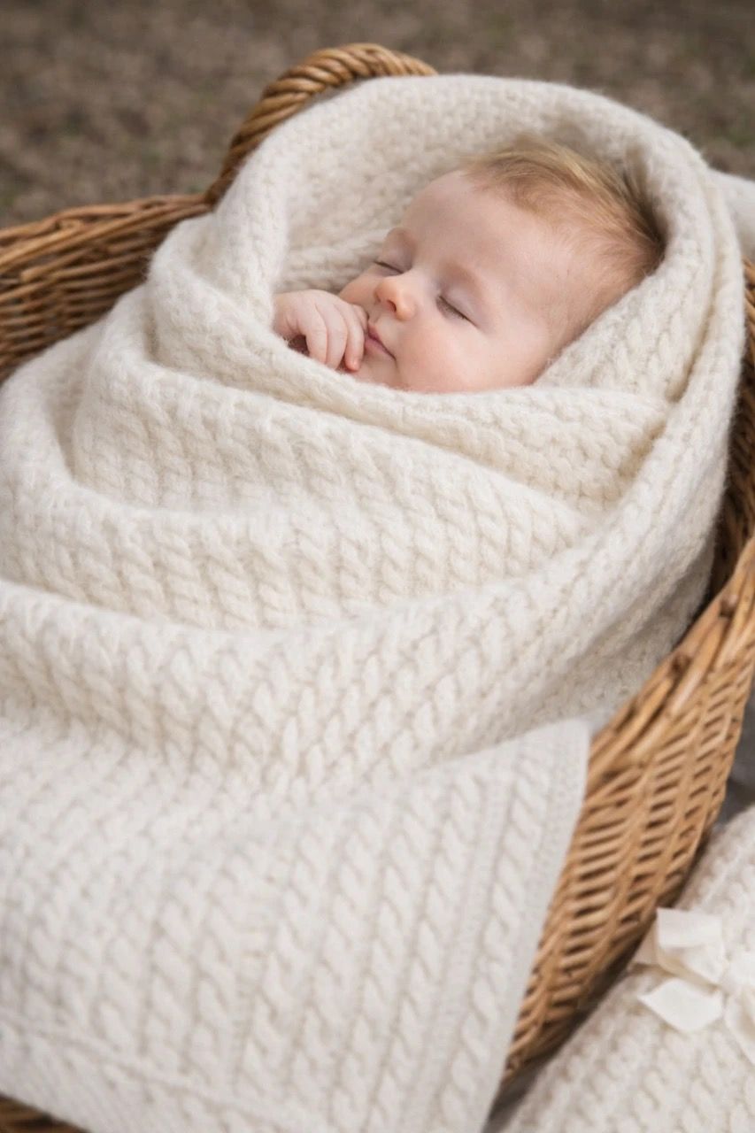 Baby wrapped in a soft white blanket, peacefully sleeping in a basket.