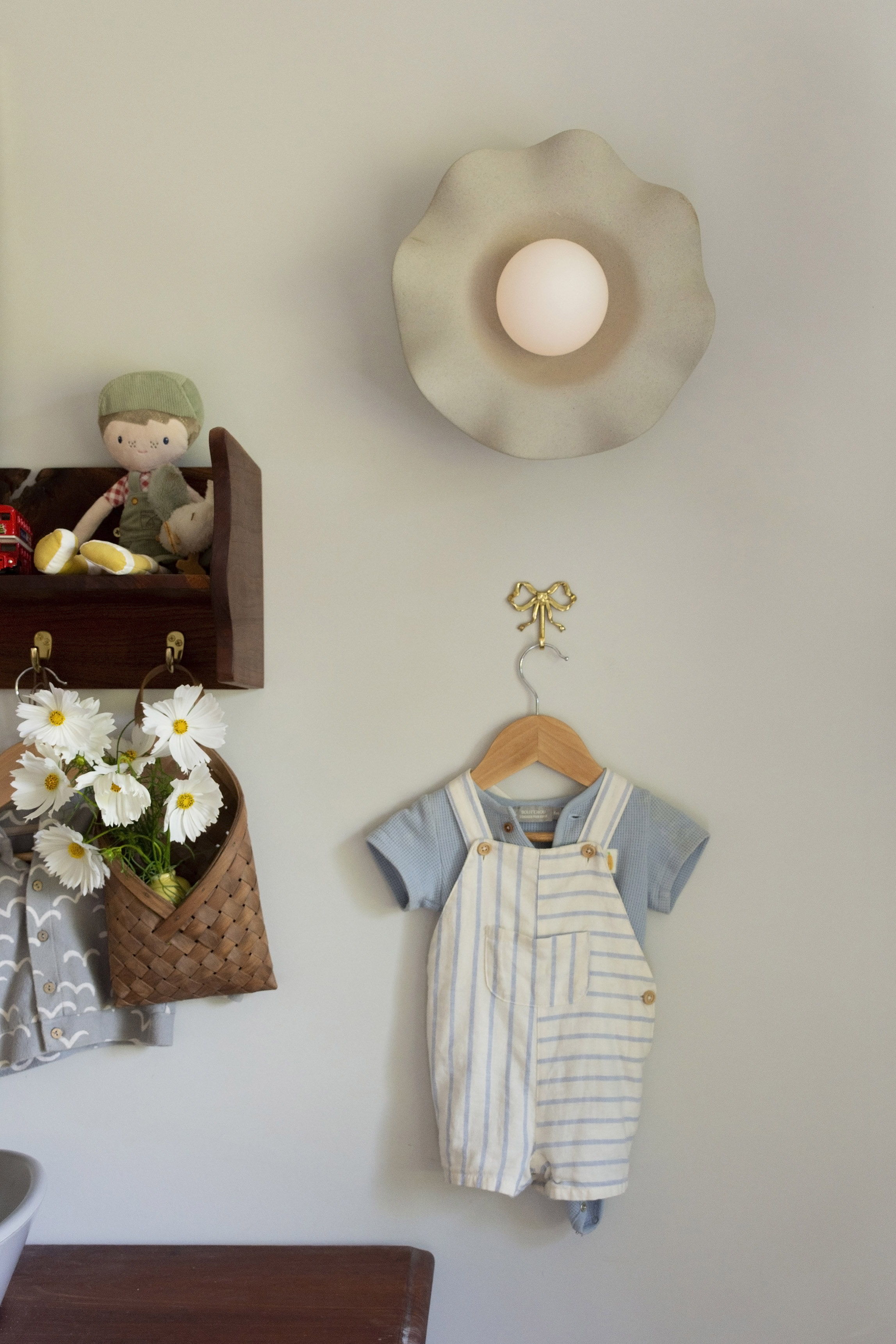 A child's outfit hanging on a wall with decorative items nearby.
