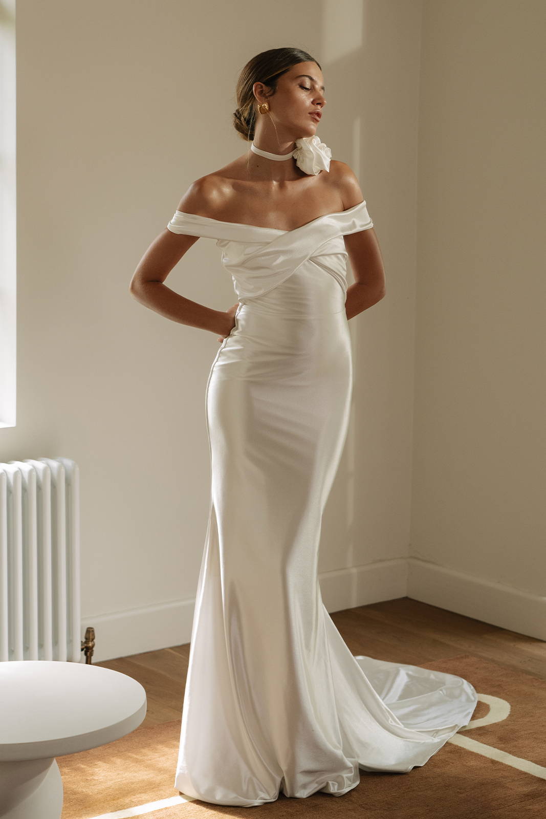 a woman standing in the Cupid gown, and off the shoulder lyrca dress with a rosette choker on