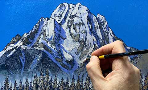 A hand painting a mountain landscape on a blue canvas.