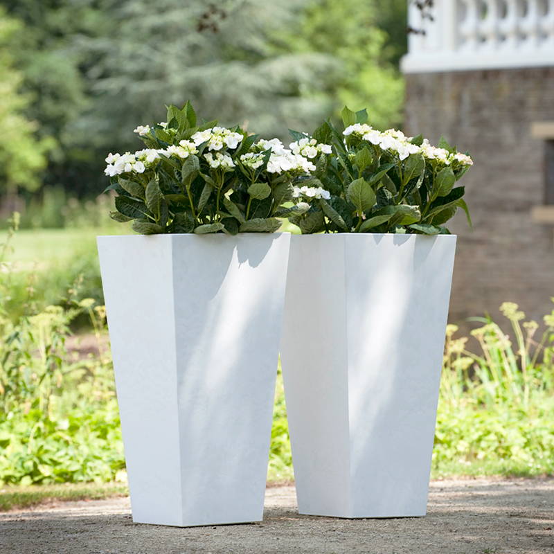 2 white ella tall planters with flowers planted inside them