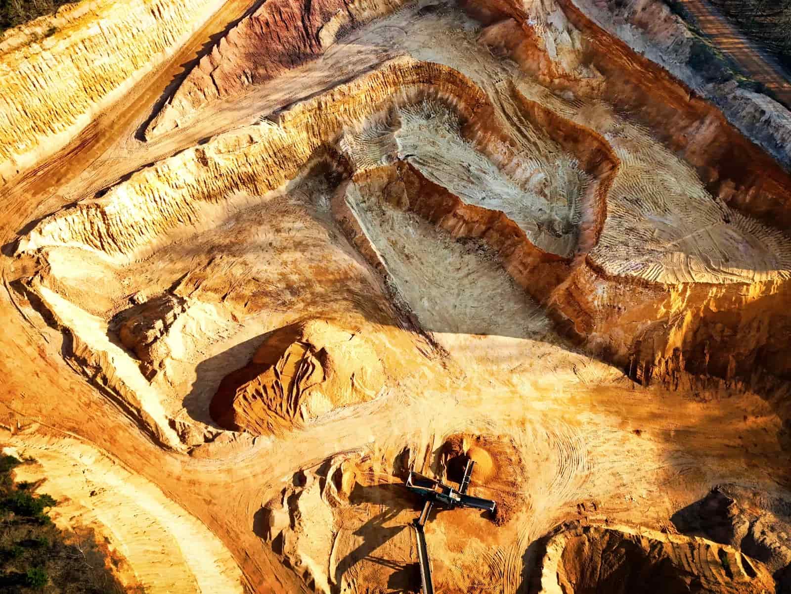 Aerial view of a large open-pit mining area showing extensive excavation zones, benches and heavy machinery