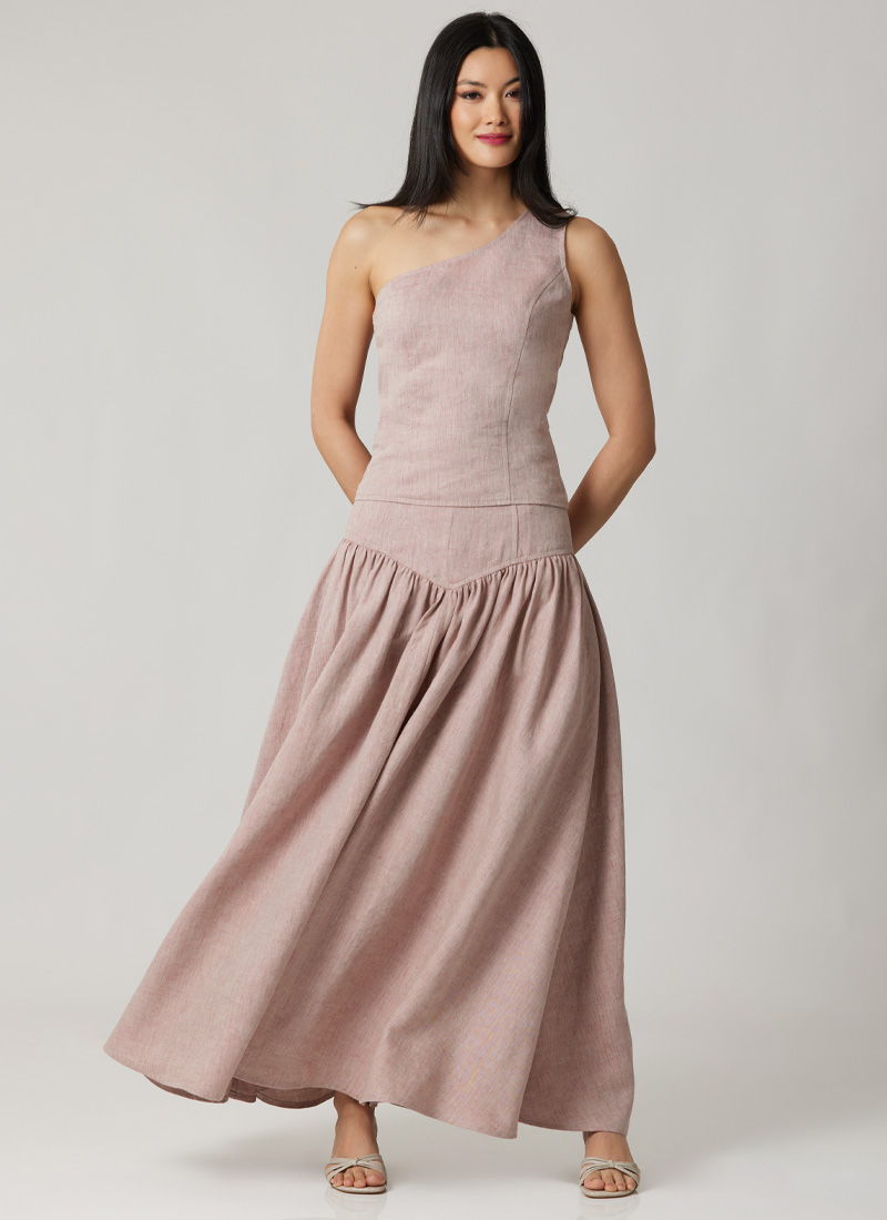 Woman in a pink, one-shoulder dress standing confidently.
