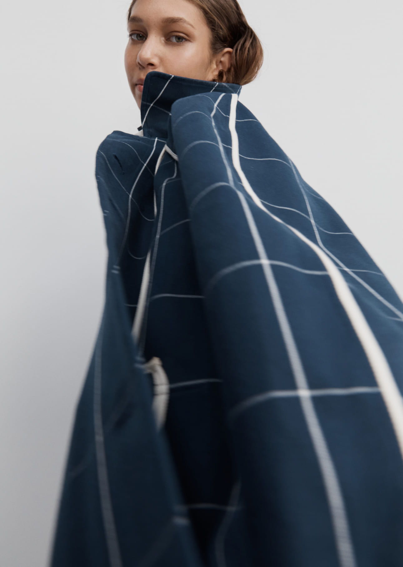 A person wearing a navy patterned garment, looking over their shoulder.