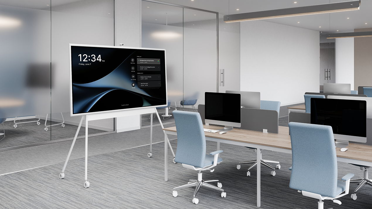 Modern office space with a large display and multiple workstations.