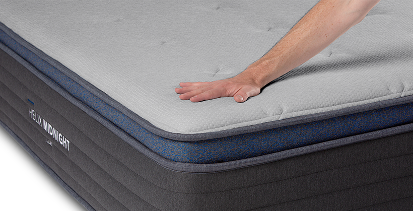 Hand on the pillow top of the medium feel Helix Midnight Luxe mattress