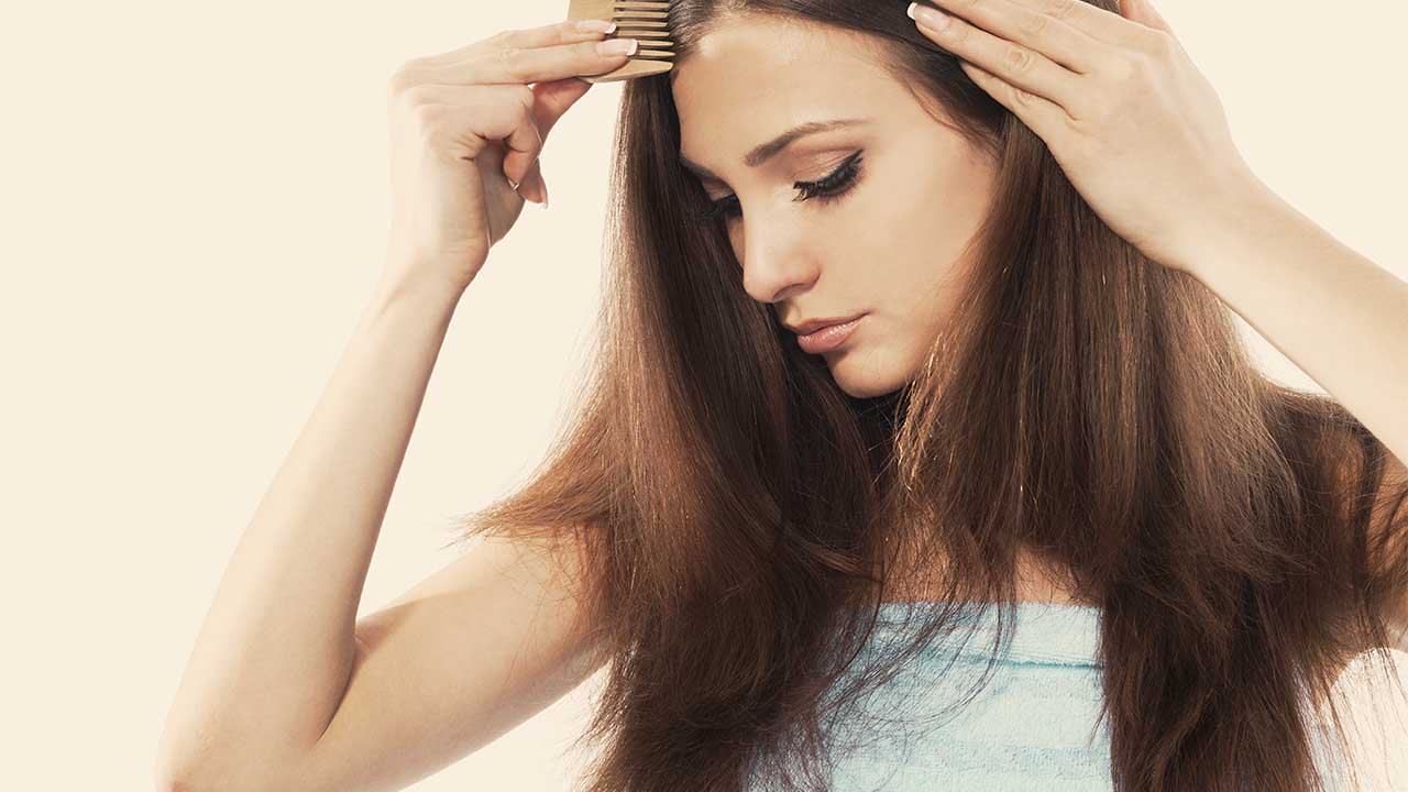 Girl with frizzy hair trying to comb through