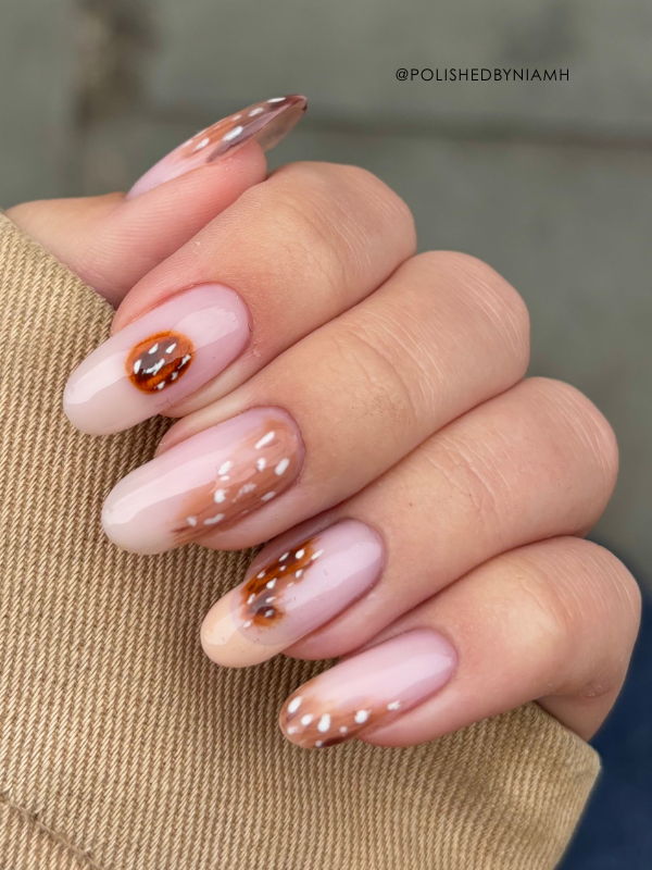 Close-up of stylish, ombre manicure with decorative accents and glitter.