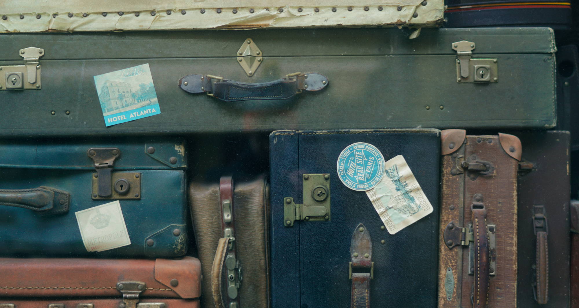 Vintage suitcases stacked on top of and next to one another.