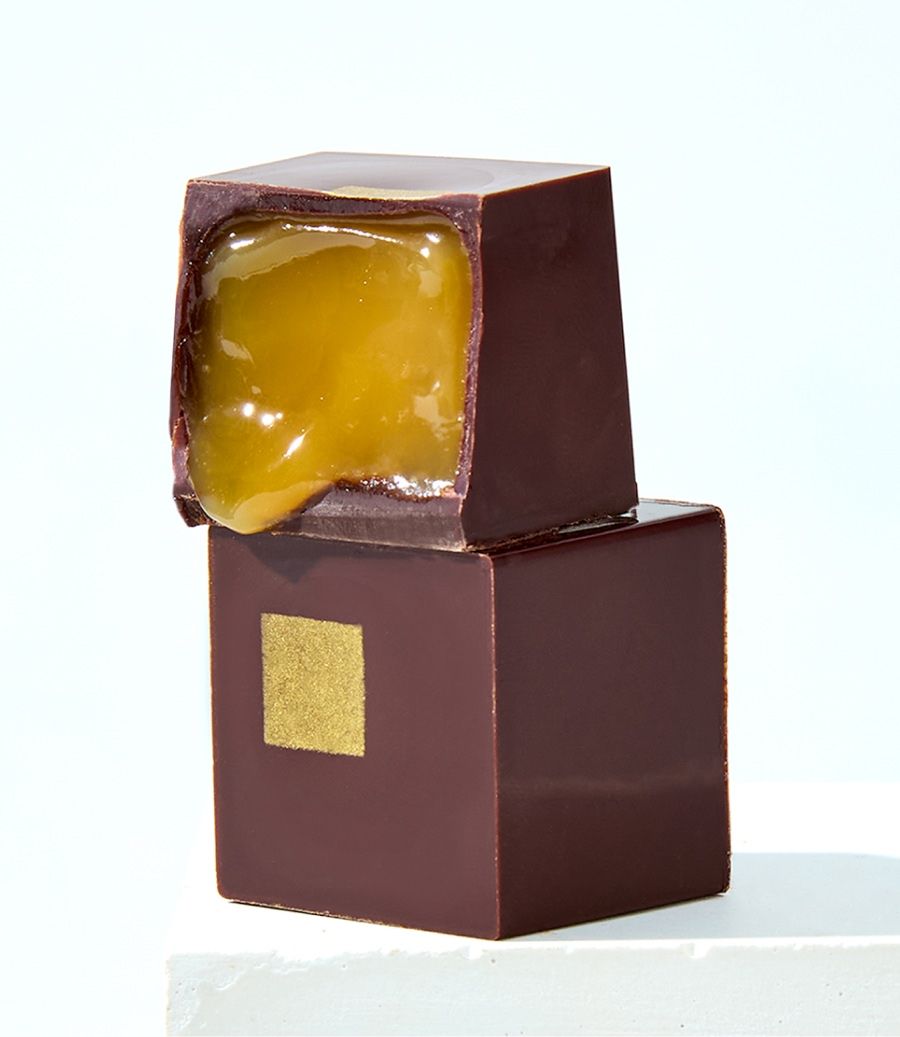 Chocolate piece with a glossy coating and a soft, yellow filling.