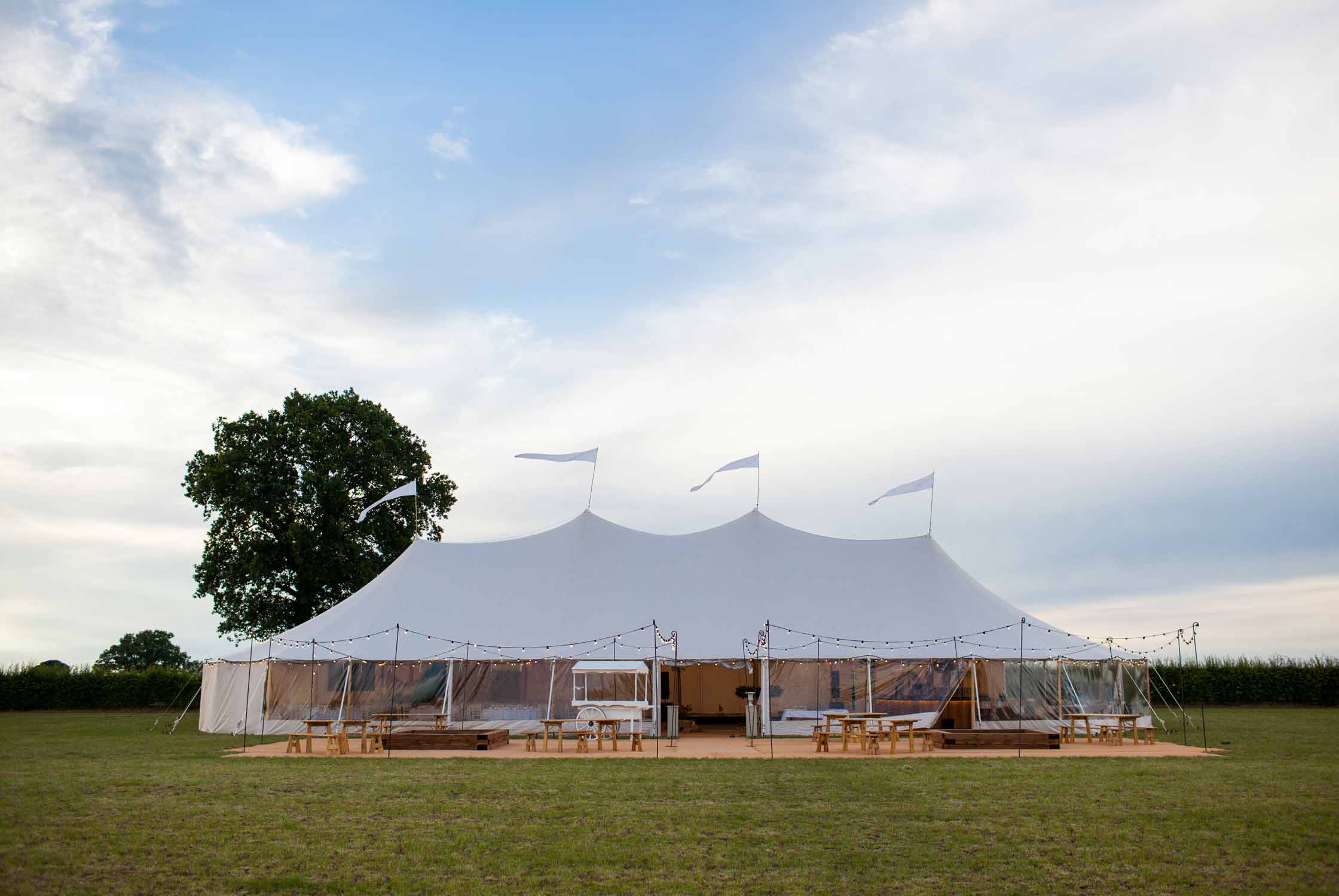 Marquee in a field with festoon lights surrounding.