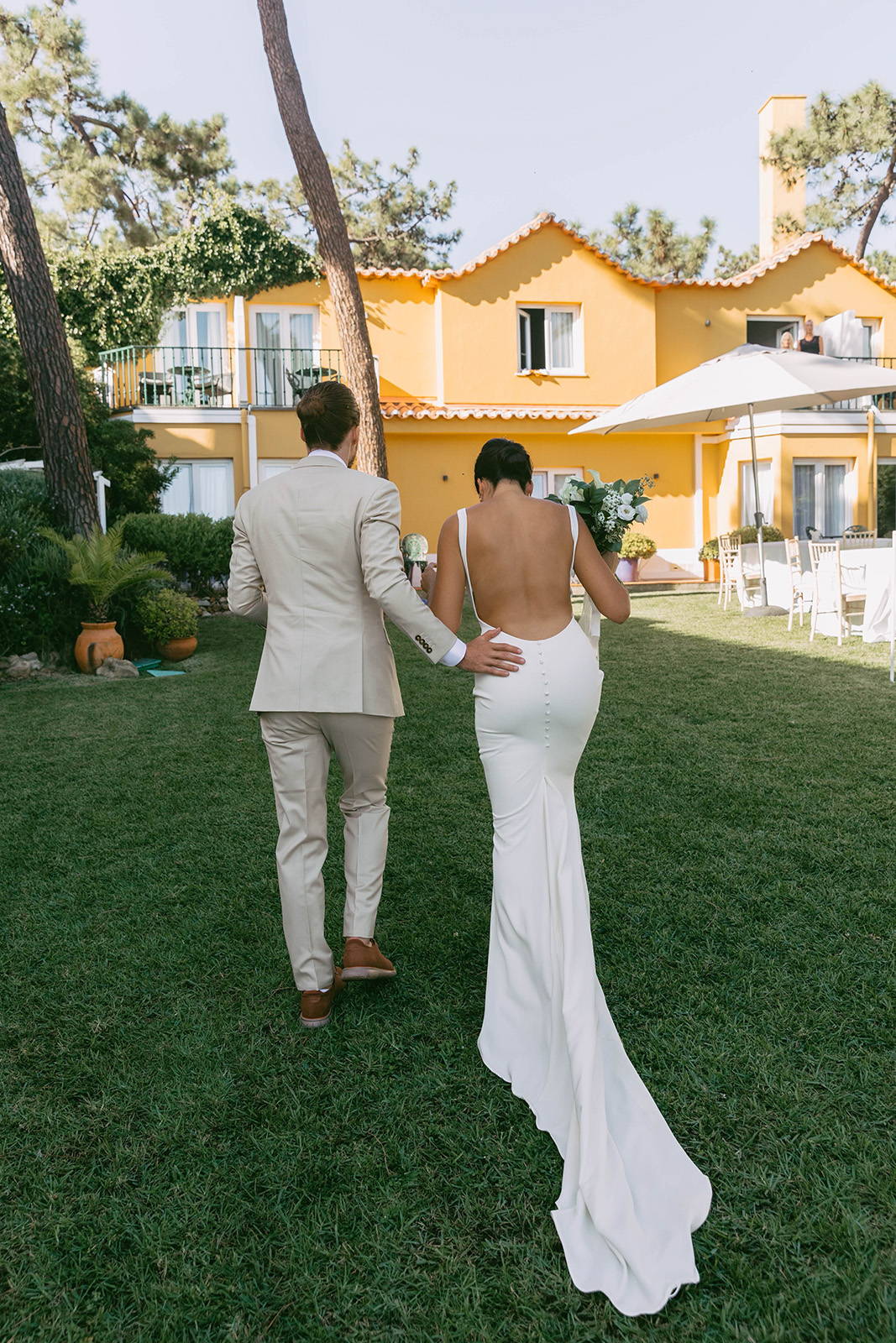 Bride and groom walking together with back detailing of the Martini gown