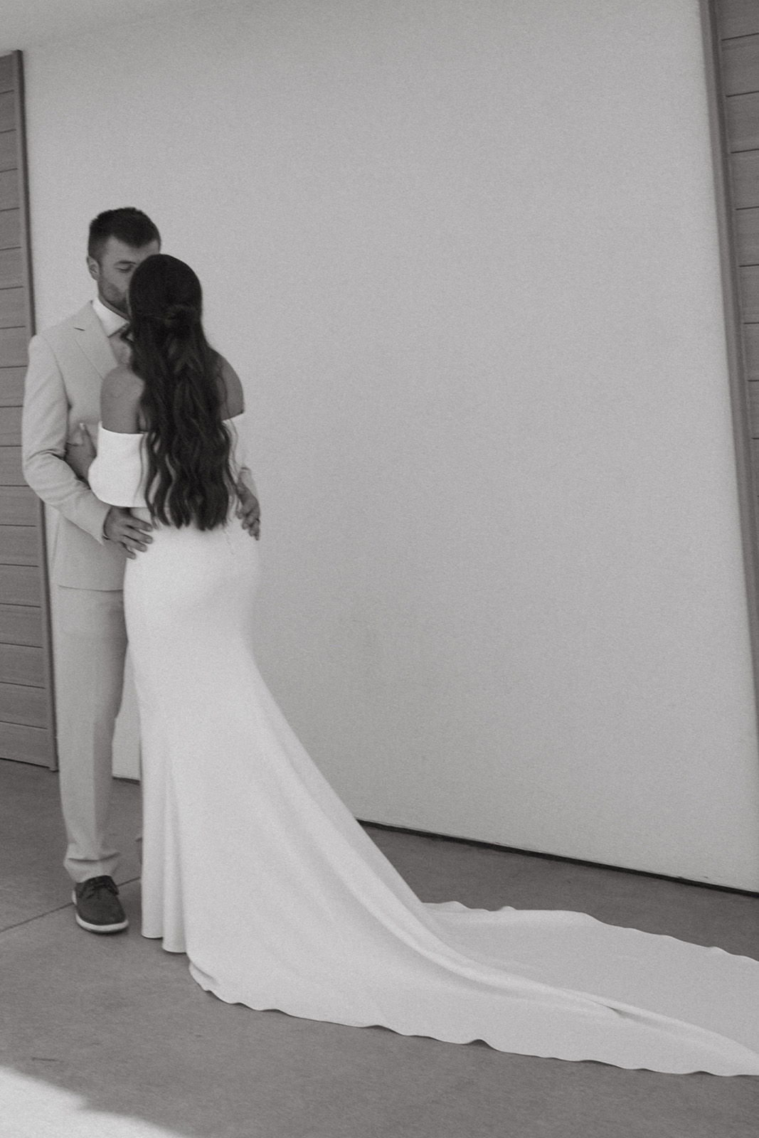 Couple embracing, woman in elegant white dress with long train.