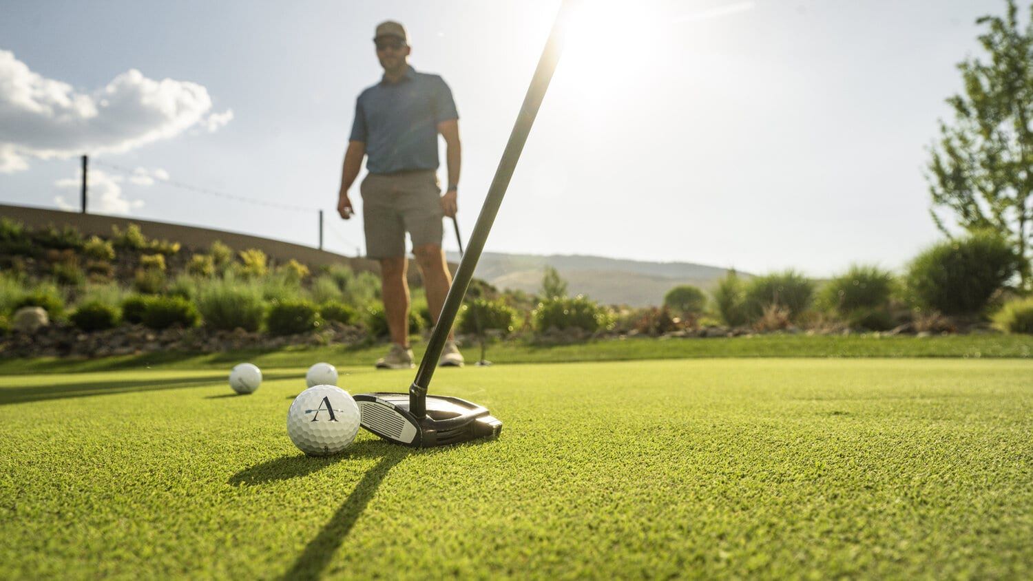 Golfer practicing putting on a sunny green course.