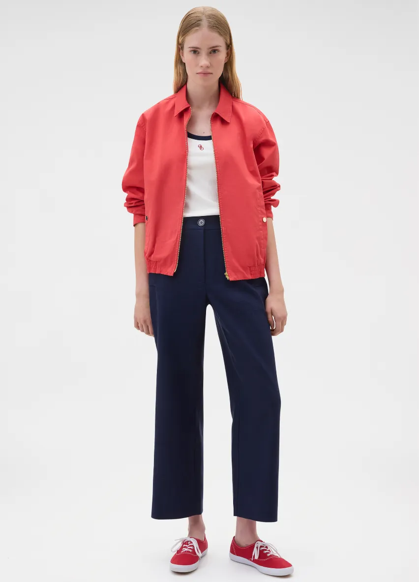 Model wearing a red jacket, white top, and navy pants with red shoes.