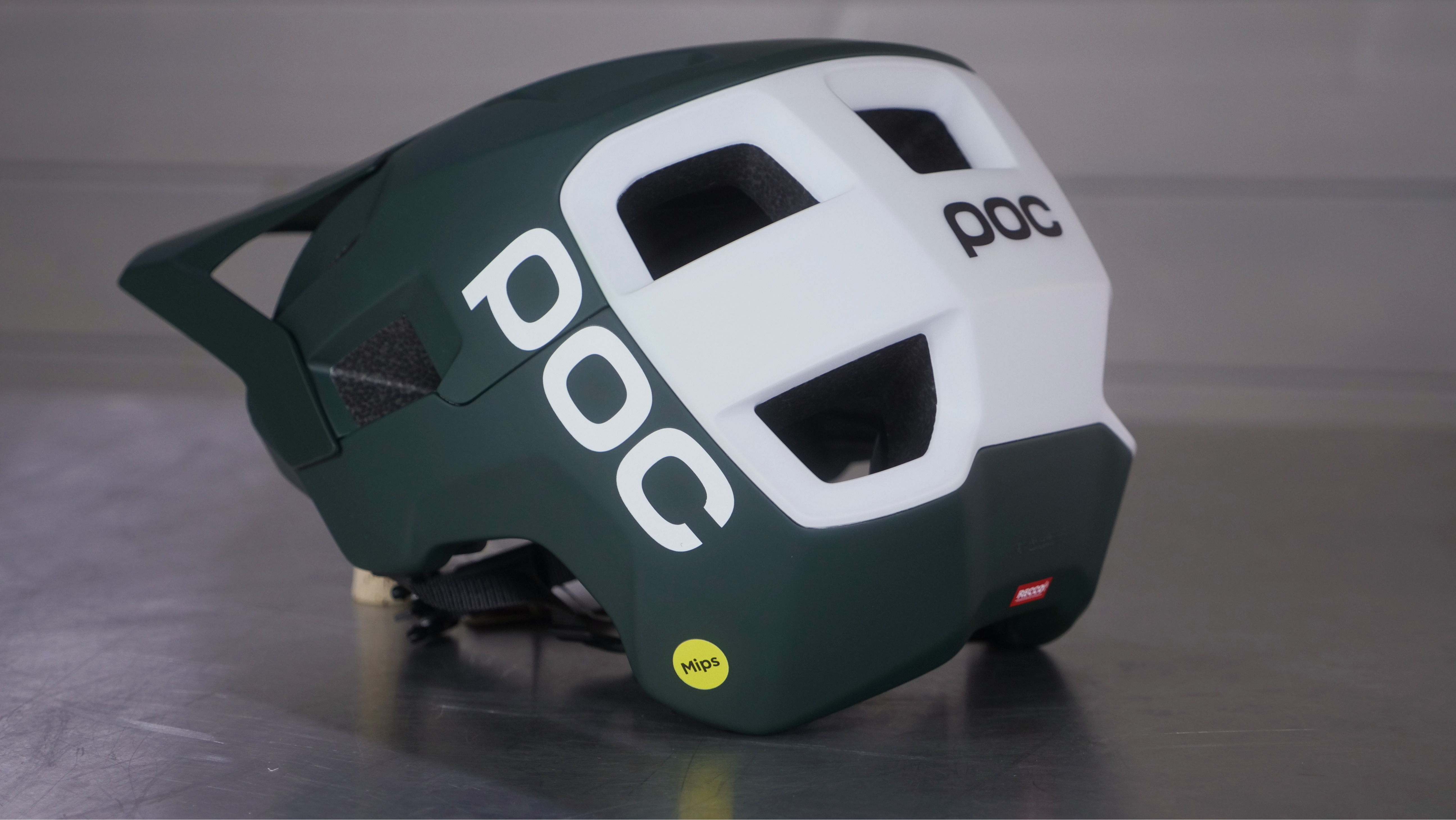 Green and white POC helmet displayed on a flat surface.