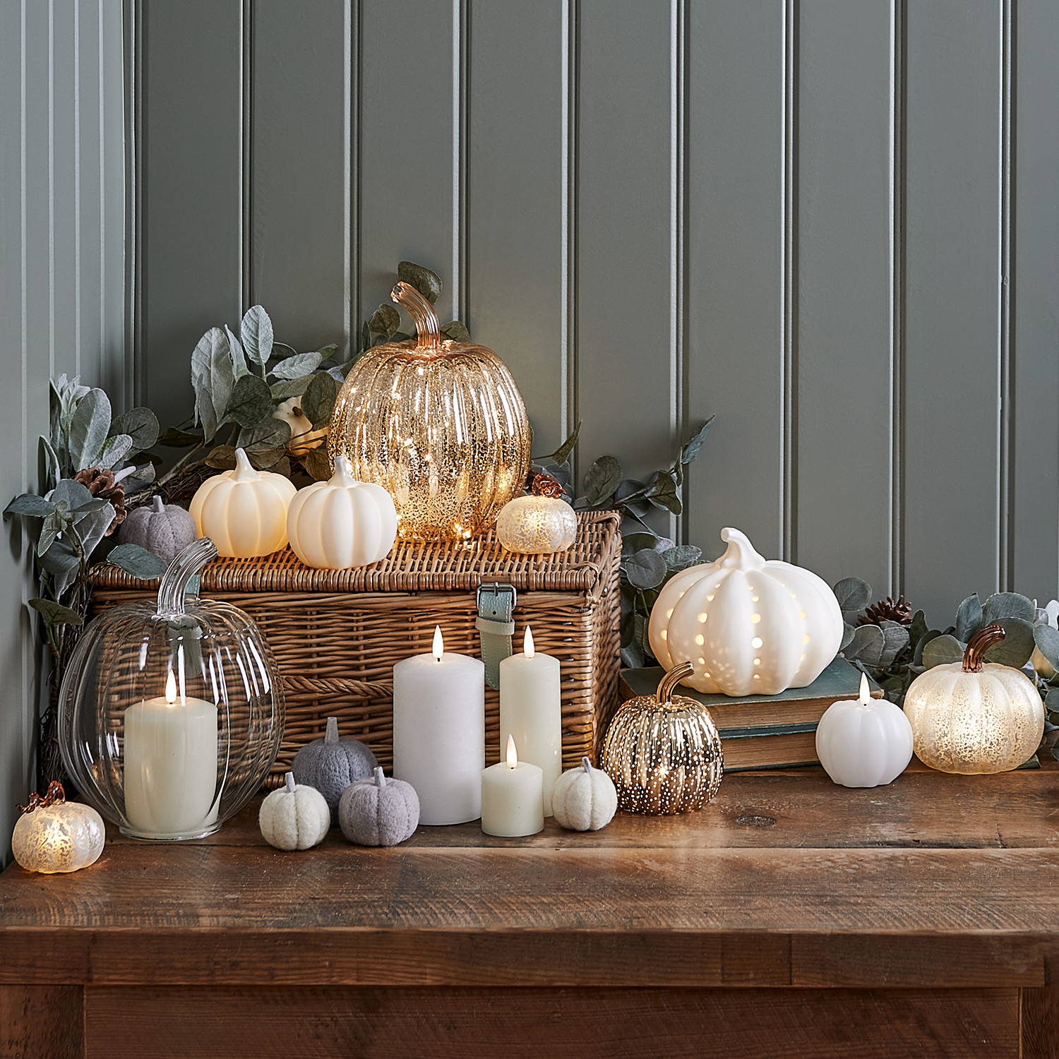 A table with neutral pumpkins, LED candles and an autumn garland.