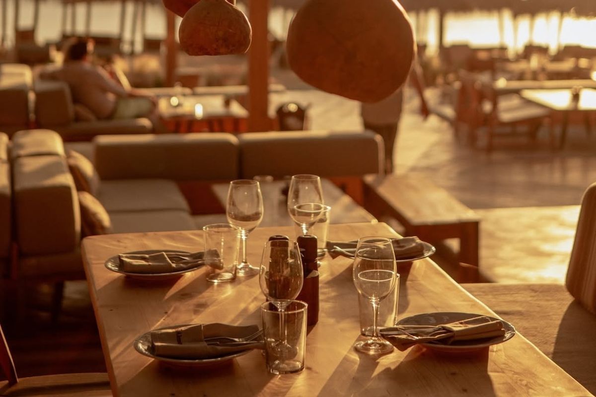 Table set for dining at a beachside restaurant during sunset.