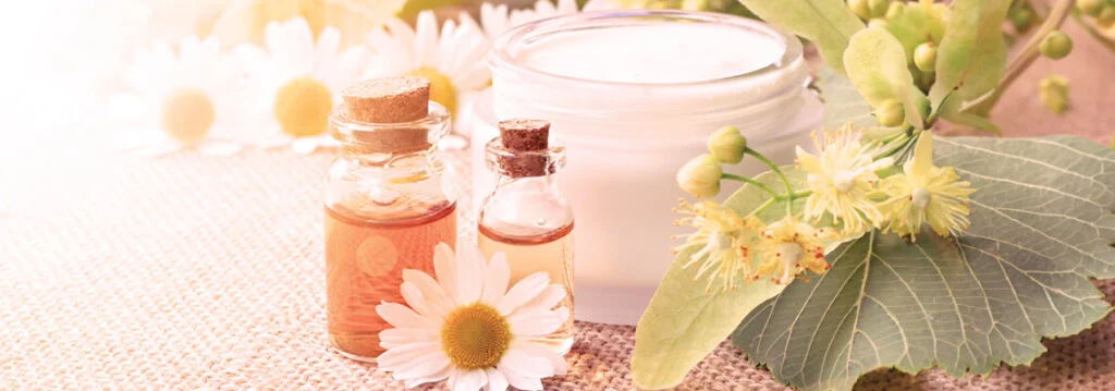 Beauty products with flowers and essential oils on a soft background.