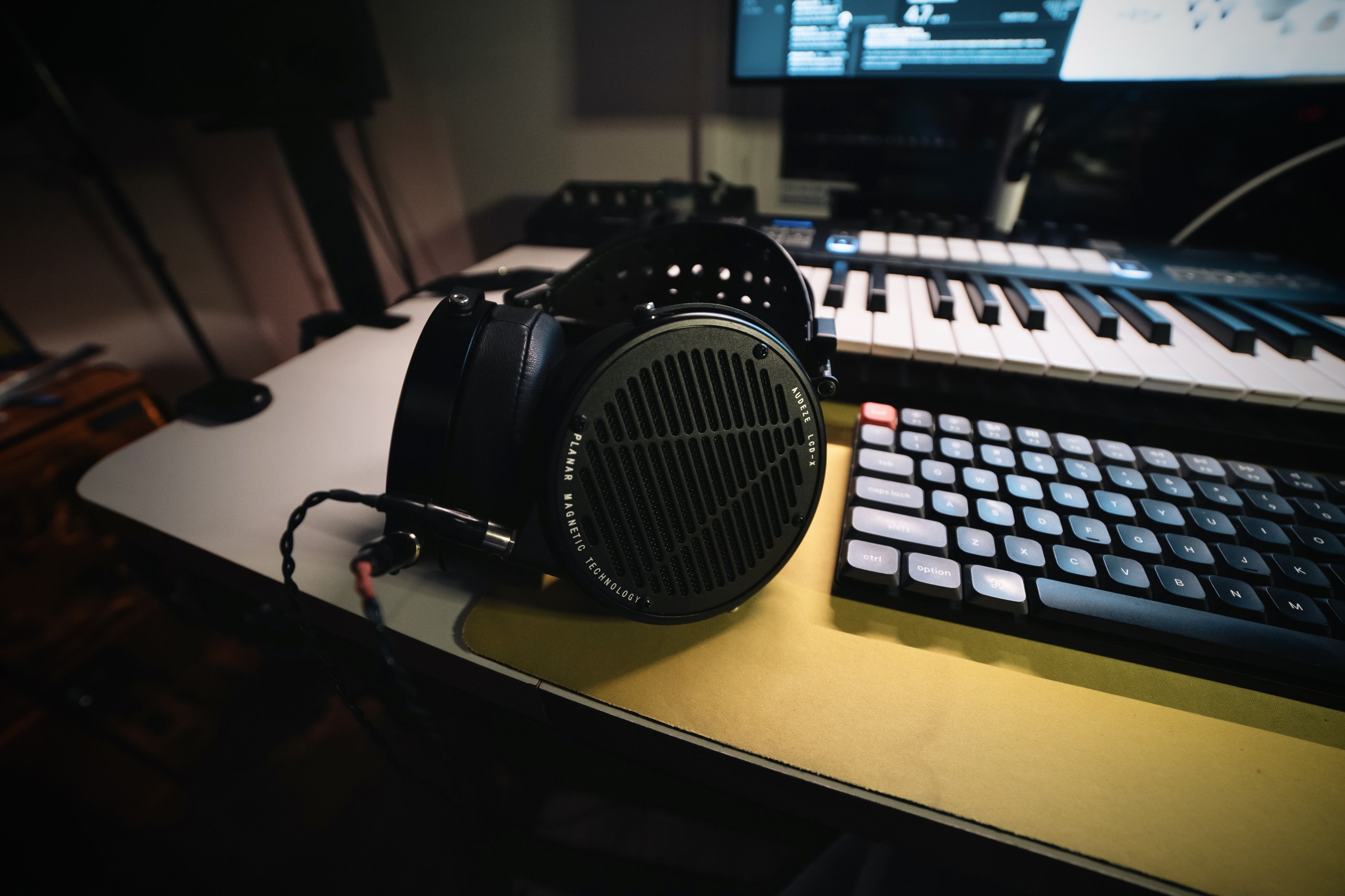 Audeze LCD-X headphones laying on table next to keyboards 