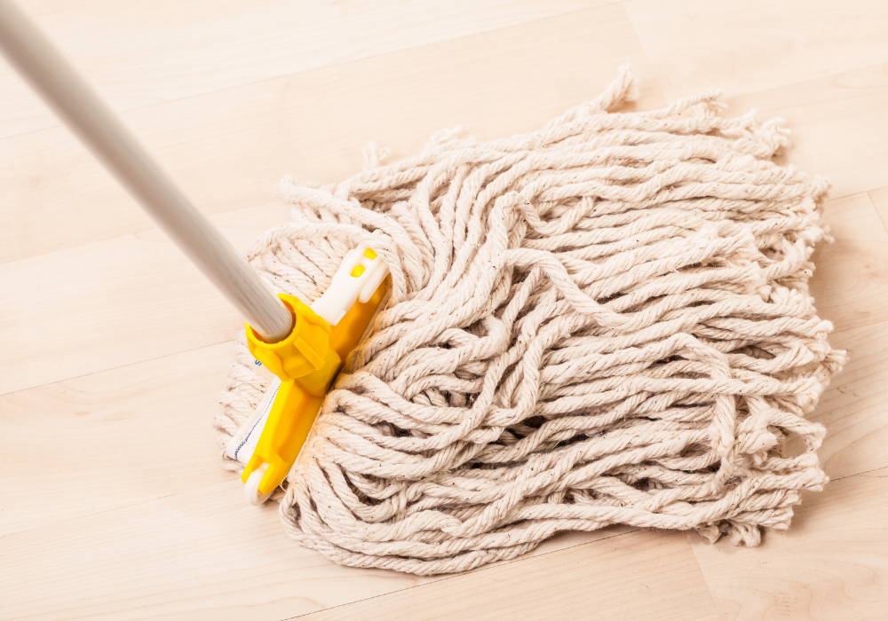 String mop with a wooden handle on hardwood floors