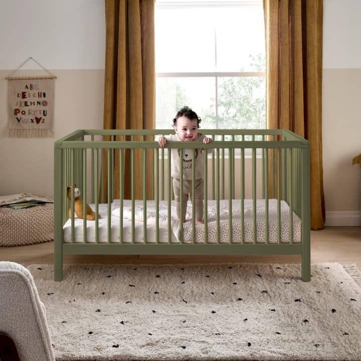 The white Mamas and Papas Flyn furniture range sits in a cream panelled nursery with a grey rocking chair.