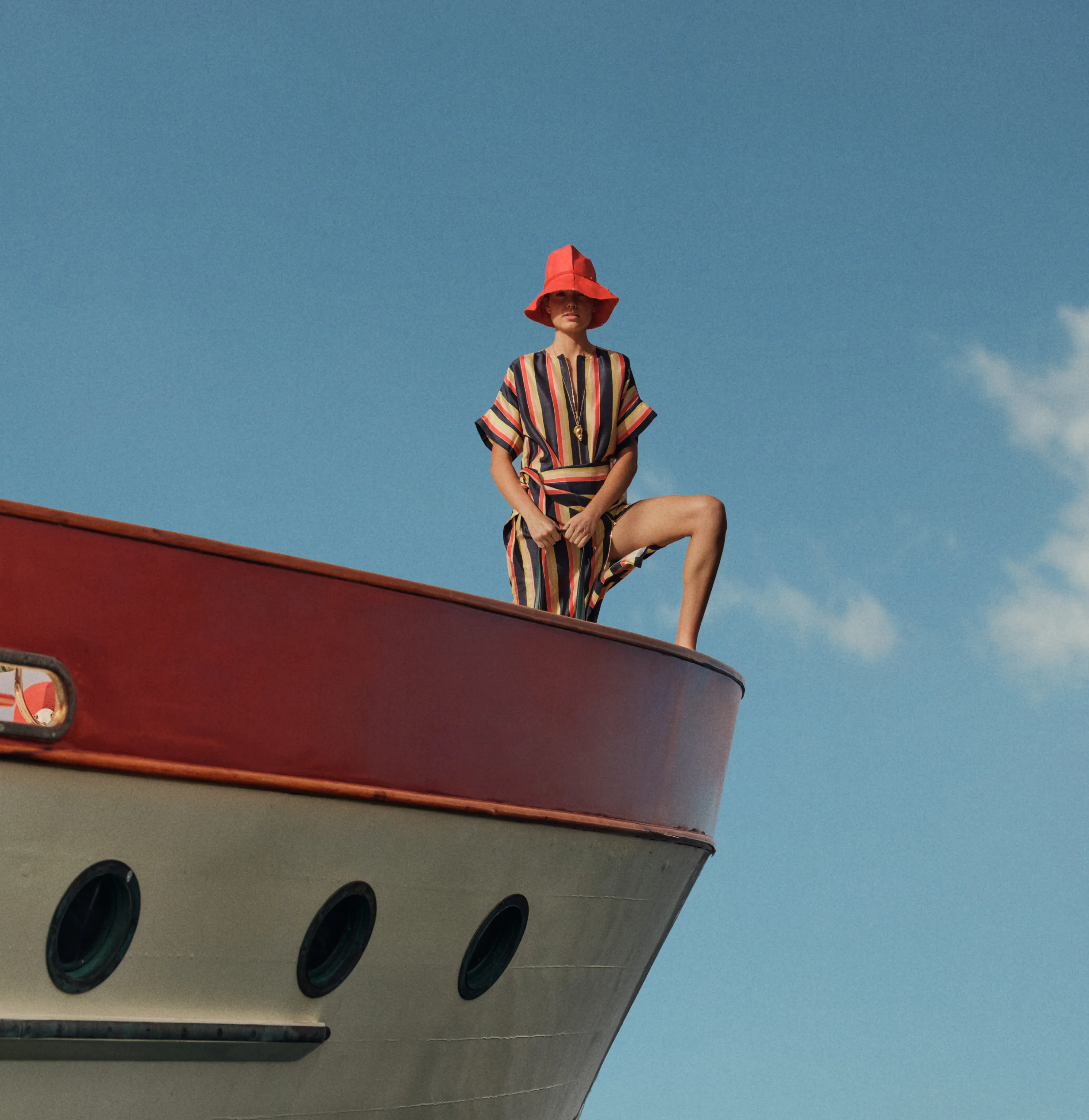 Person in a striped outfit sitting on the edge of a boat.