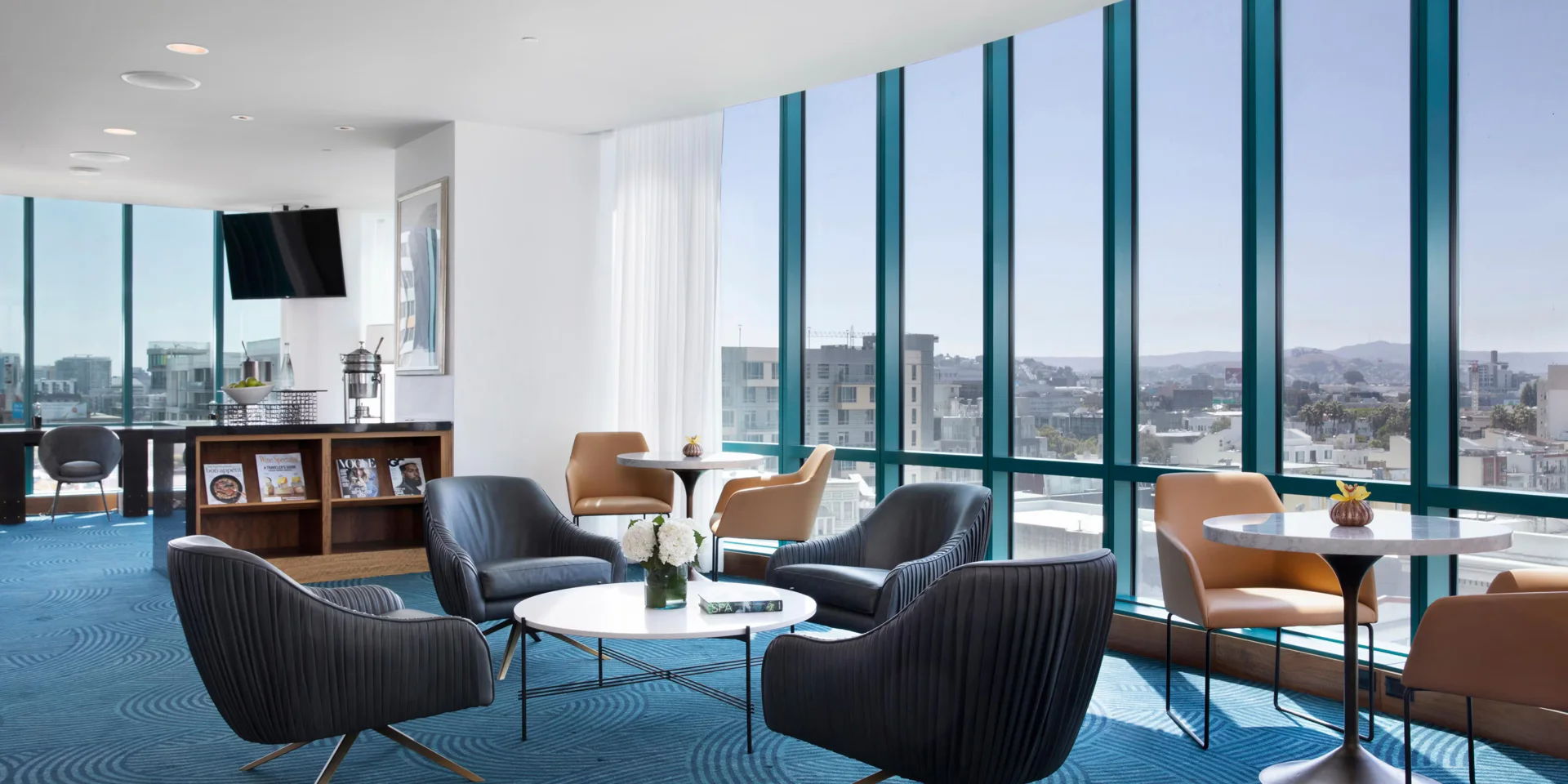 Modern office lounge with large windows and stylish seating.