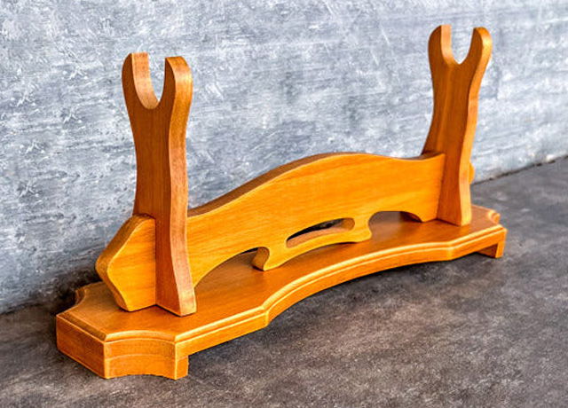 Wooden display stand with curved base and forked supports.