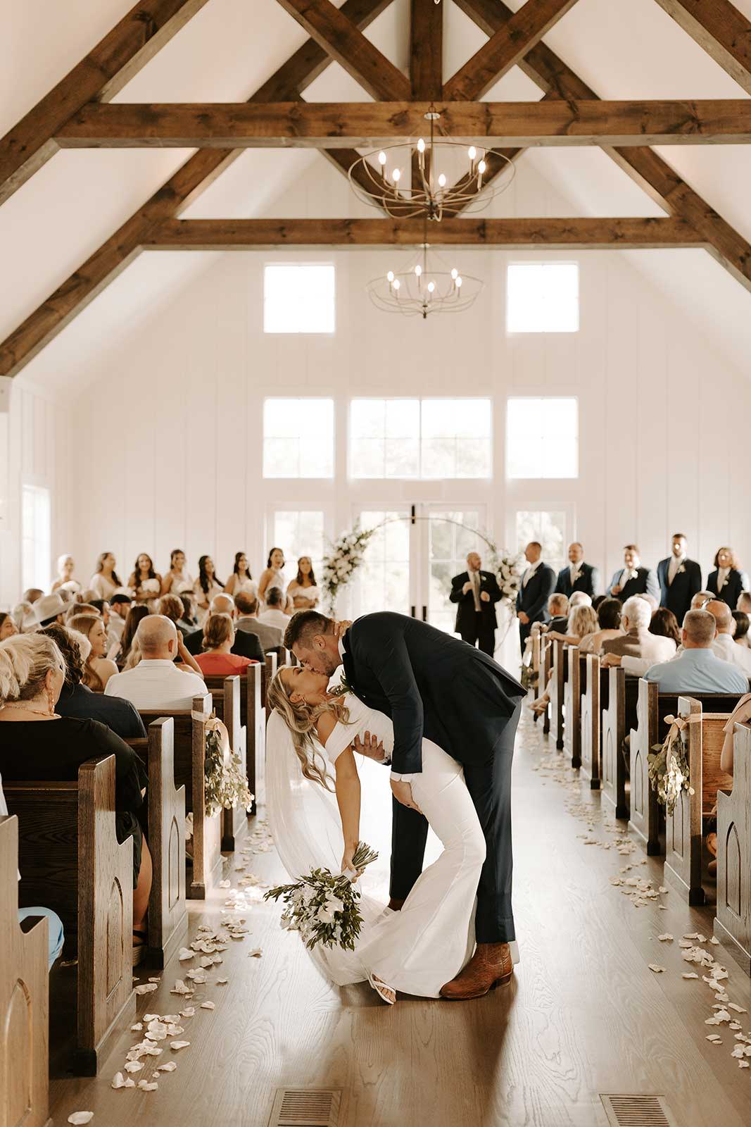 Bride and groom sharing a kiss at the end of the aisle