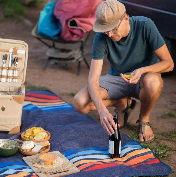 Person setting up a picnic on a Rumpl mat