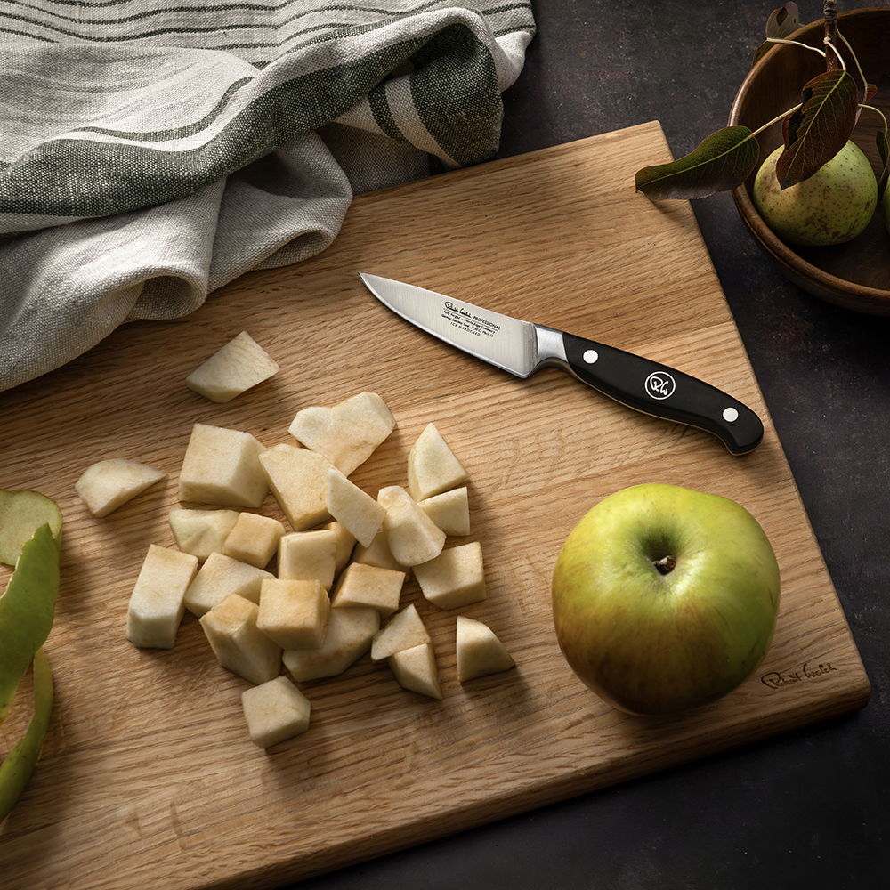 Chopped fruit on a wooden cutting board with 9cm Professional Paring Knife and an apple.