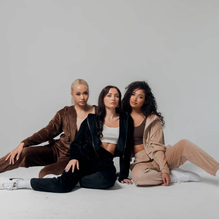 three female models wearing sacre velour apparel sitting