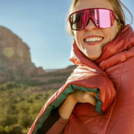 A person wearing sunglasses and a red Rumpl blanket