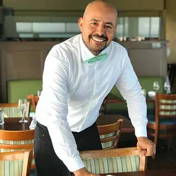 A waiter wearing a seafoam bow tie.