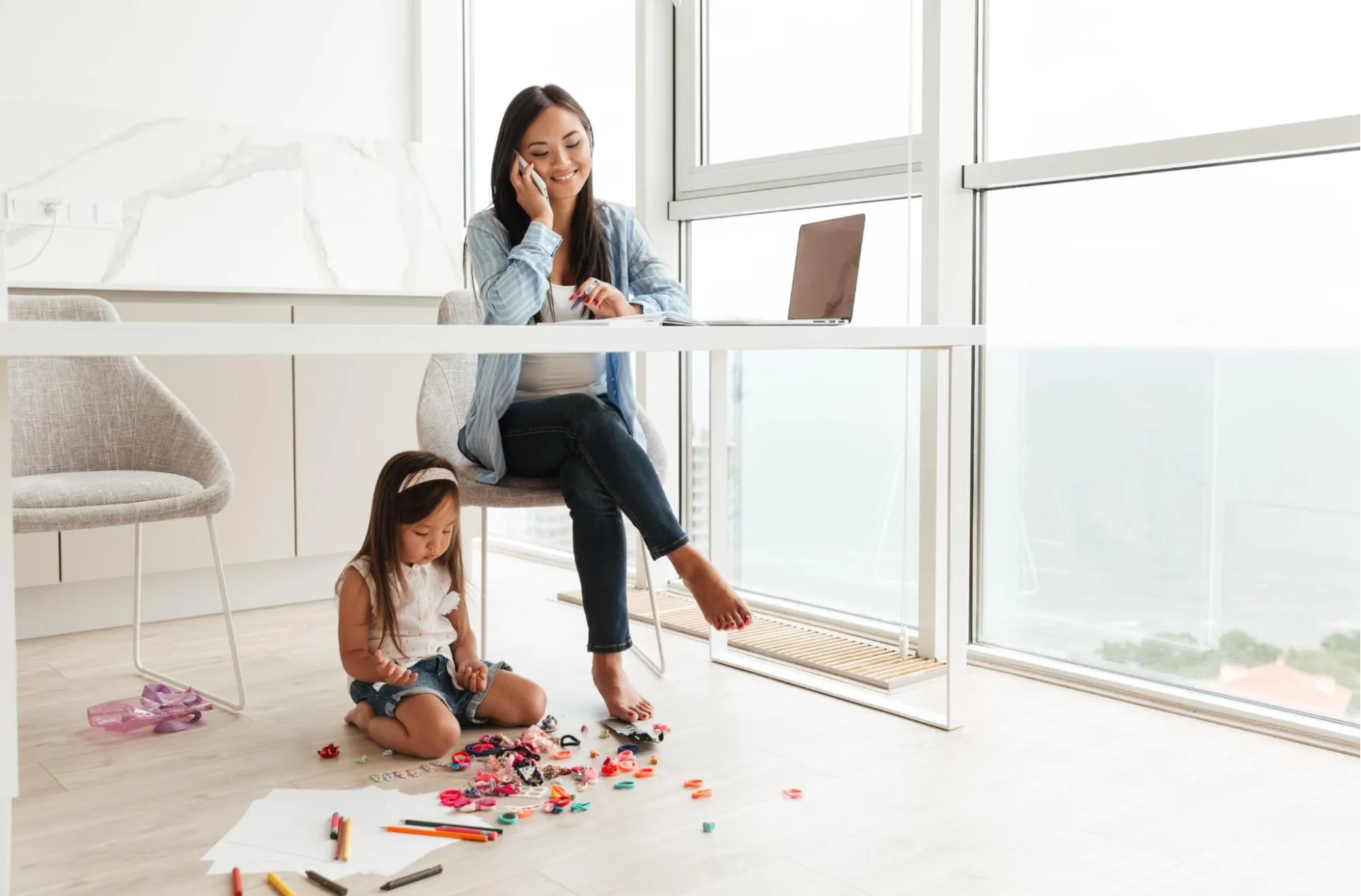 Mother working from home with child playing under her desk