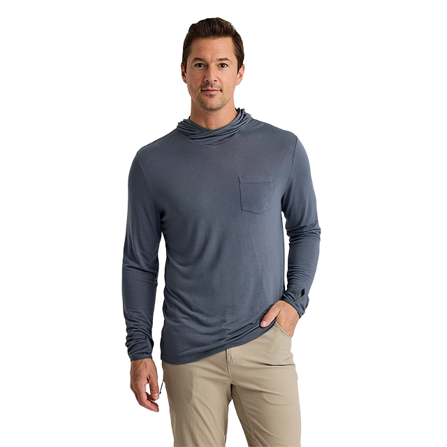 Man in a blue long-sleeve shirt with a pocket, standing against a plain background.