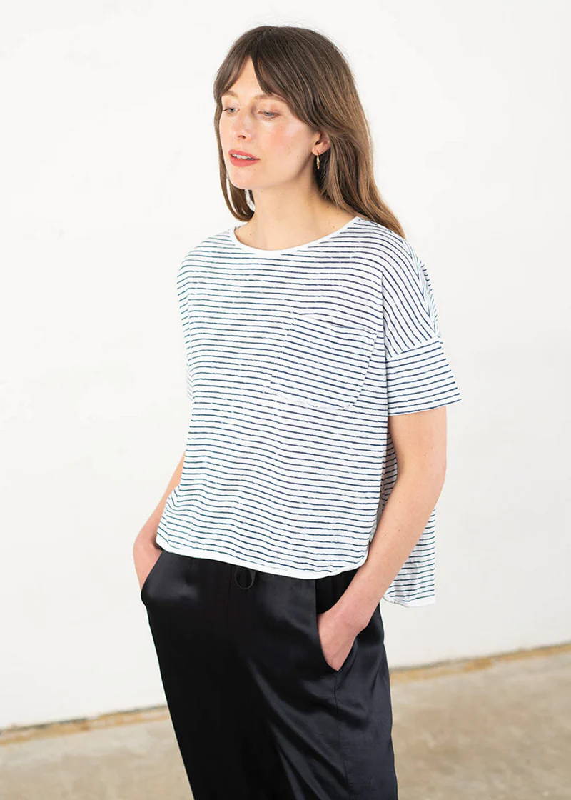 A model wearing a short sleeved boxy t shirt with small black and white stripes