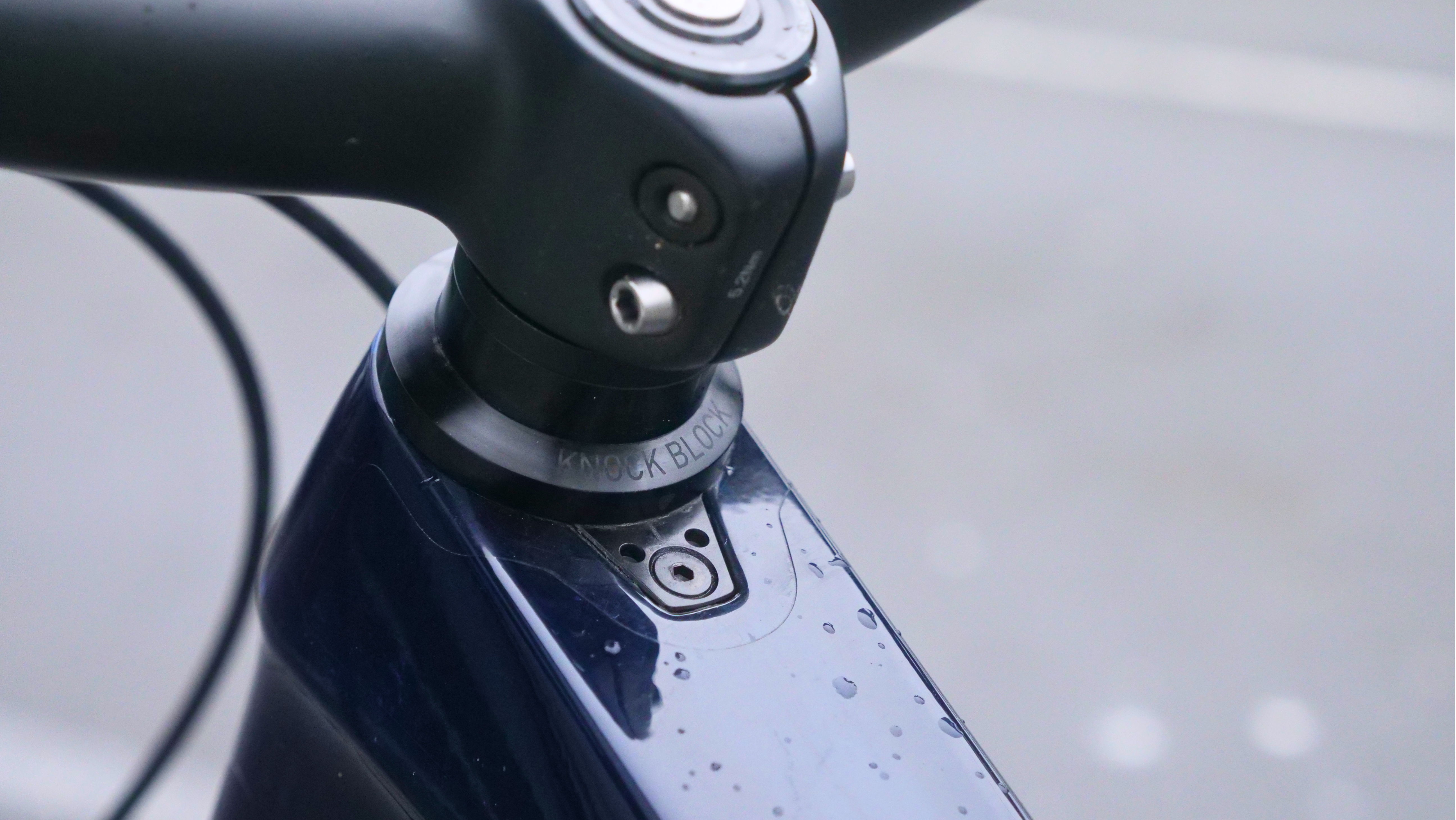Close-up of a bicycle handlebar and stem with raindrops.