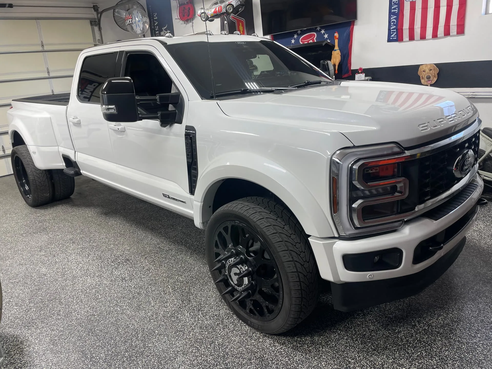 Front three-quarter Robert's white Ford F450 Platinum dually with black spiked wheels in garage photo 3