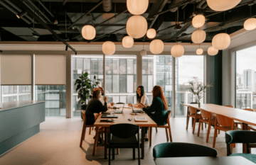 Modern office meeting room with people gathered around a large table.