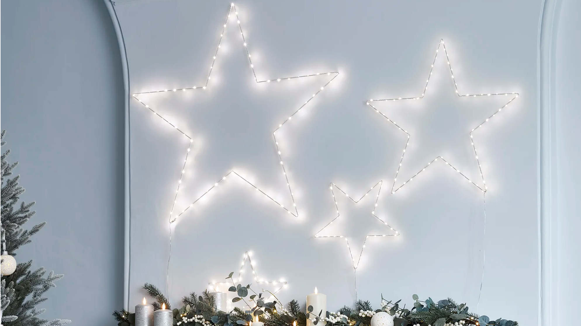 Leuchtende Osby LED Sterne verschiedener Größen an der Wand über einem Kaminsims