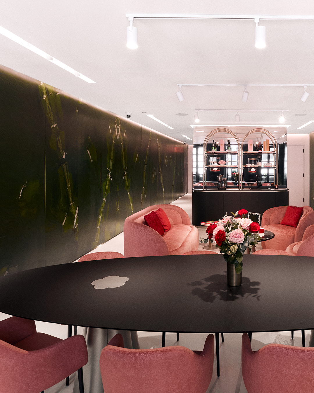 Modern interior with pink chairs, black table, and floral centerpiece.