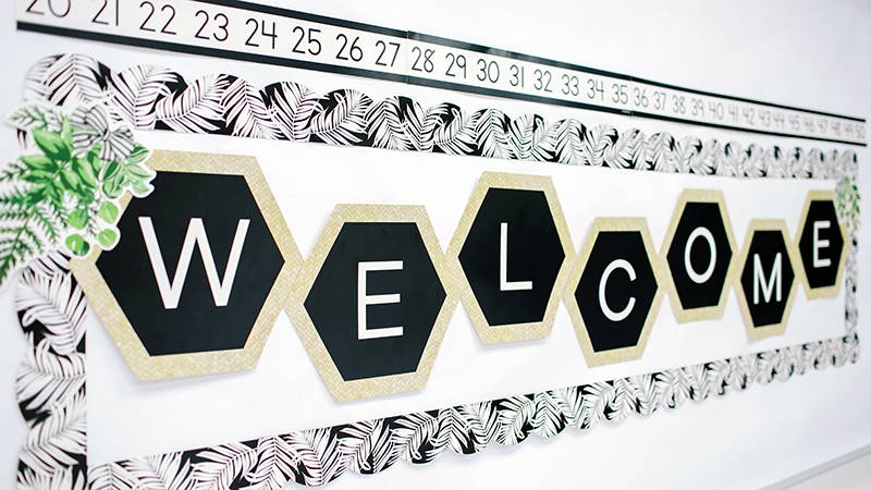Simply Boho Welcome Bulletin Board Set surrounded by black and white borders on classroom wall