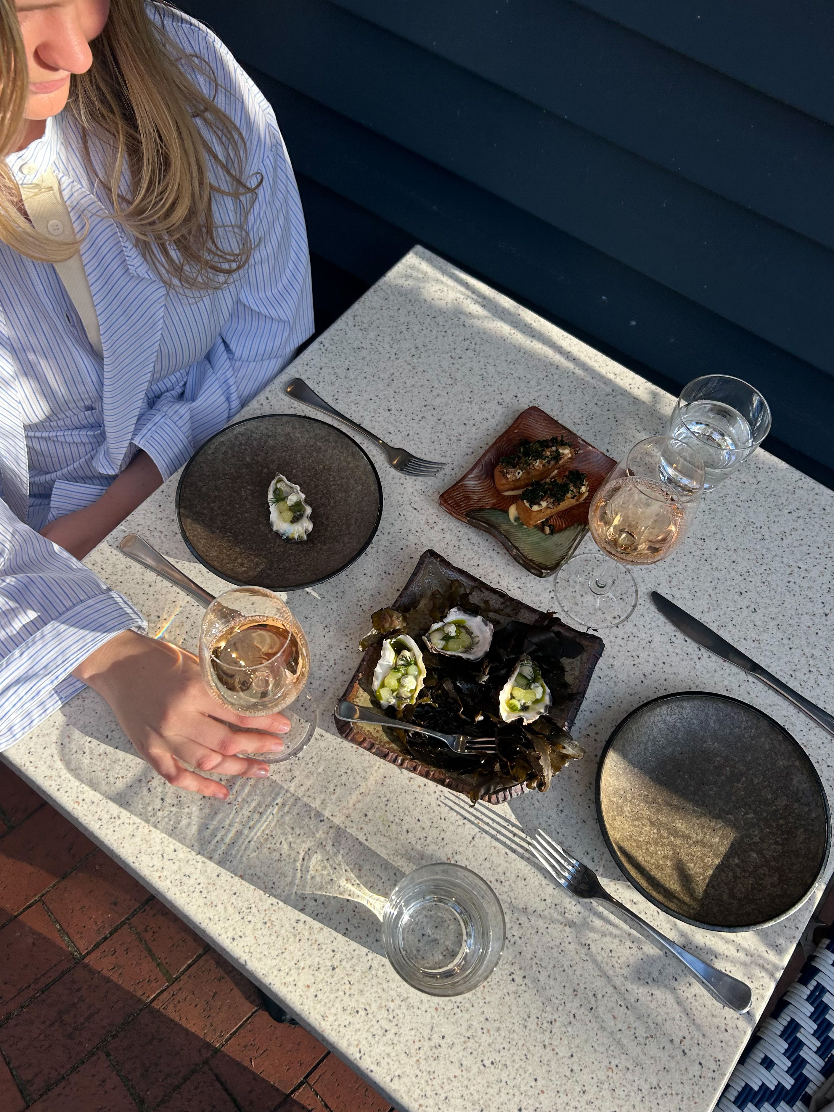 A woman holding a drink at a table with various dishes.