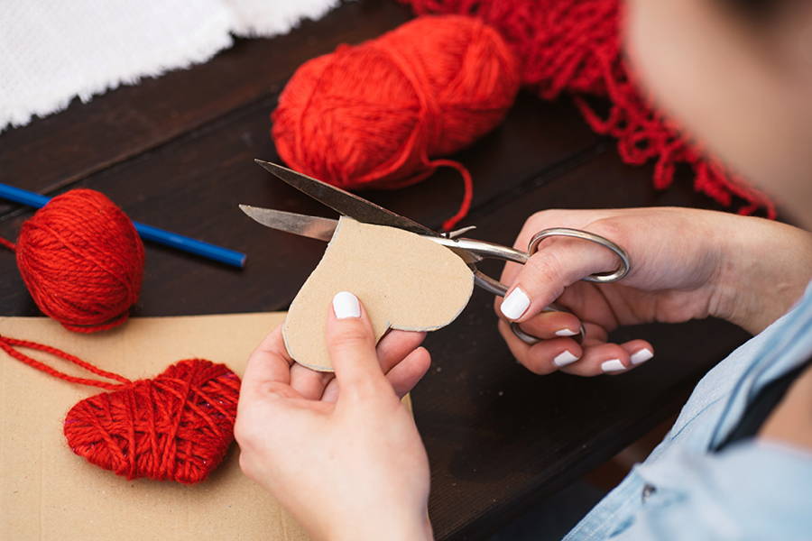 hands holding scissors and cutting cardboard heart for a craft