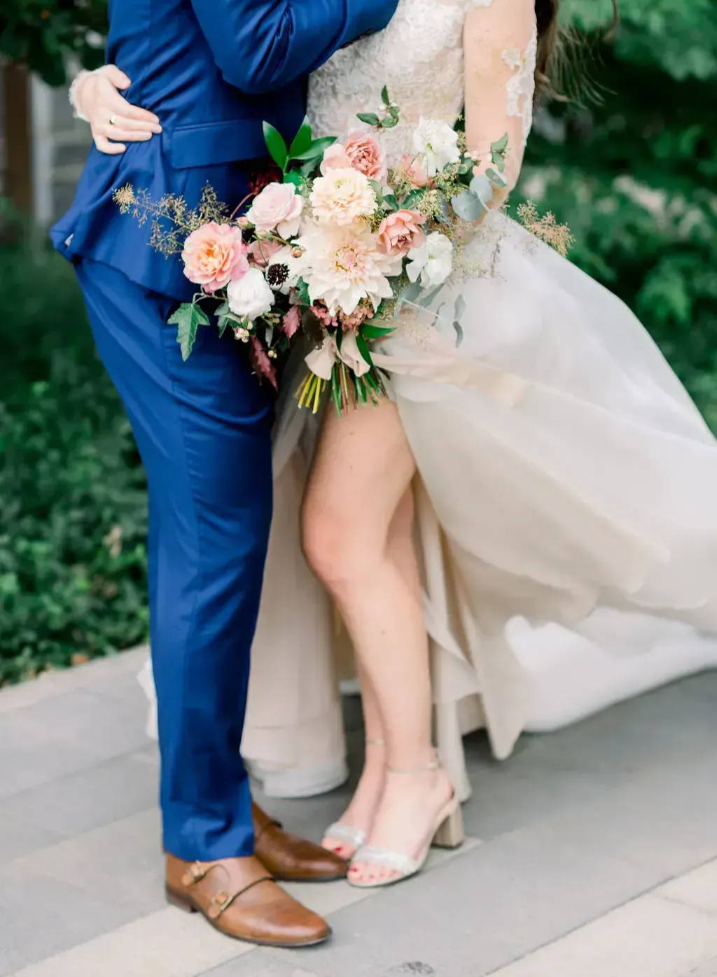 shoulder down picture of couple embracing while bride holds her pink and blush bridal bouquet in the front