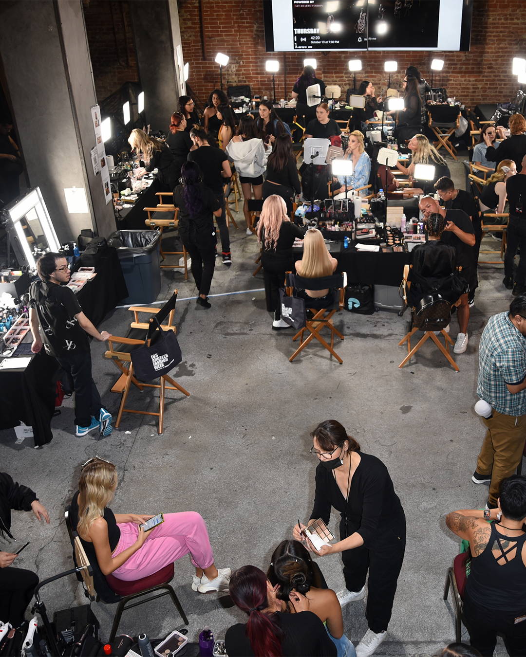 Image of an aerial view of the backstage at LA Fashion Week where models are getting styles for the runway.