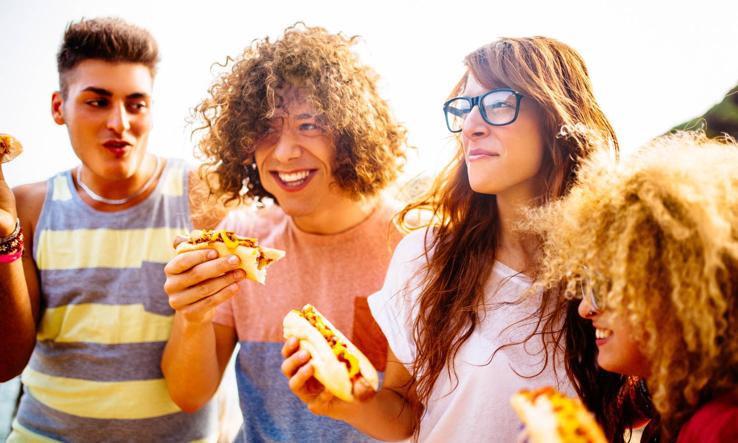 four young people eating hotdogs