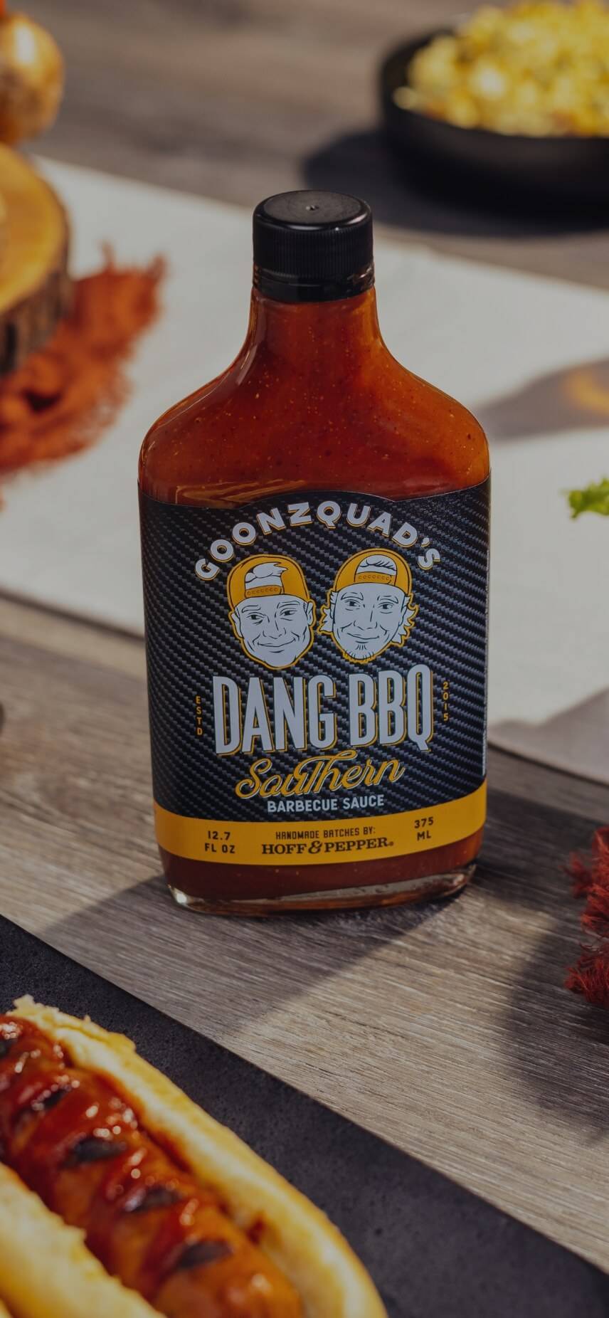 Bottle of Dang BBQ Sauce seating next to a plate of cheese burgers